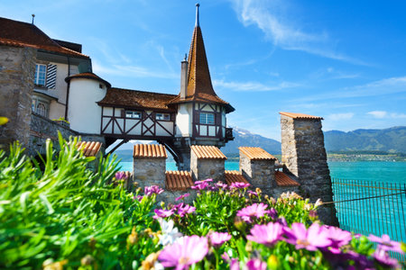 Oberhofen Switzerland castle view on the tower in the water from forts walls with flowers in flowerbed on foregroundのeditorial素材