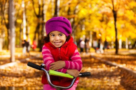 Little black 3 years old black girl riding a bicycle in the park resting on sternの写真素材