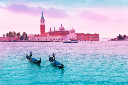 Two gondoliers on gondolas in front of Chiesa di San Giorgio Maggiore in Veniceのeditorial素材