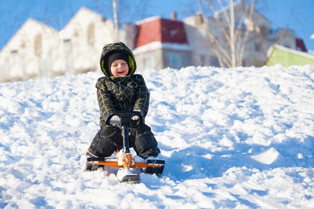 Little 3 years old boy sliding on the sledge scooter on winter dayの写真素材