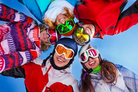 Five happy smiling friends standing in circle with ski masksの写真素材