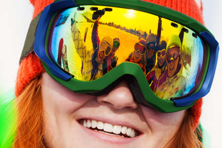 Happy smiling snowboarder in ski mask portrait with reflection of his friends on the maskの写真素材