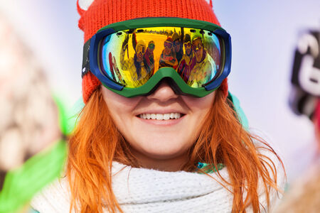 Happy young woman in ski mask with reflection of her friends on the maskの写真素材