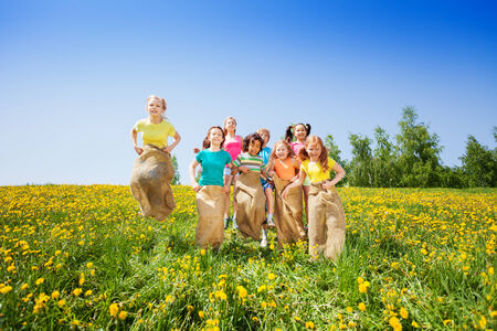 Funny kids jumping in sacks playing together in summerの写真素材