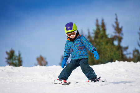 Small boy in ski mask and helmet learns skiingの写真素材