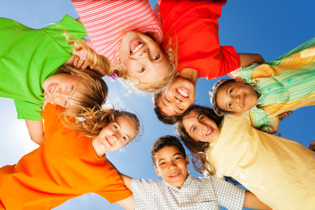 Happy kids close in circle on sky backgroundの写真素材