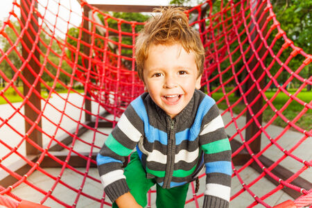 Cute smiling kid on red grid of playgroundの写真素材