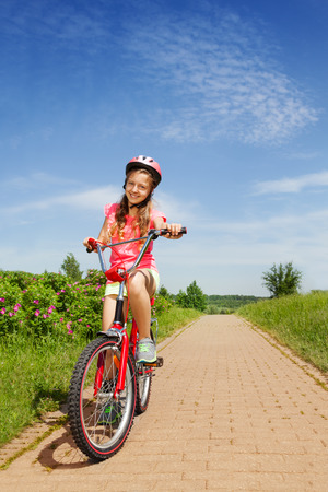 Teenage girl in red sitting on a bikeの写真素材