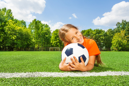 Girl holding close football, smiling and layingの写真素材