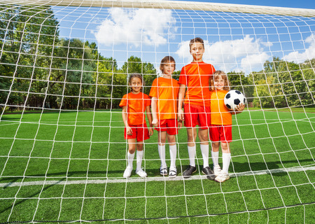 Children of different height stand with footballの写真素材