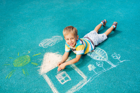 Little boy drawing chalk image on the groundの写真素材