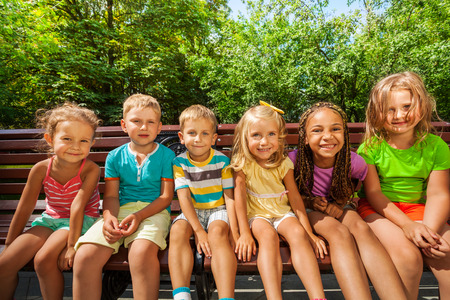 Row of children on the bench in parkの写真素材