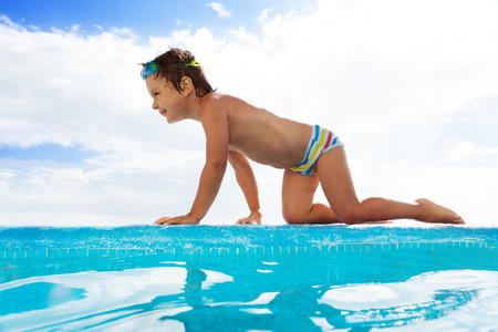Small kid with goggles crawls on stoned boarderの写真素材