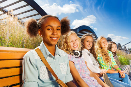 Girls smiling and sitting on the bench in summerの写真素材