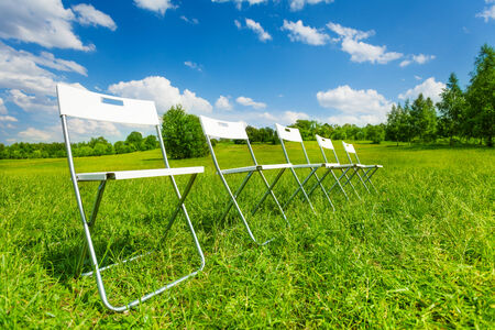 White chairs standing in a row on green grassの写真素材