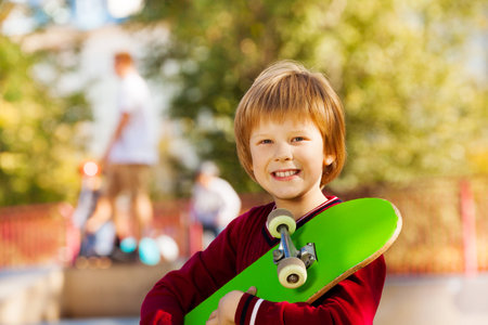 Close-up view of smiling boy with green skateboardの写真素材