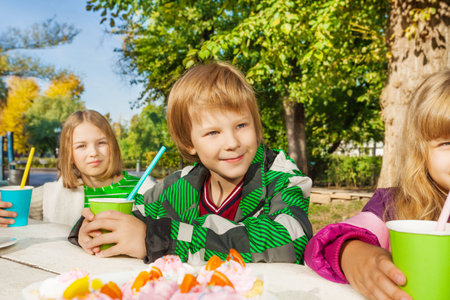 Happy children sitting at wooden white tableの写真素材