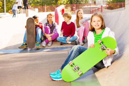 Kids sit behind and girl in front with skateboardの写真素材