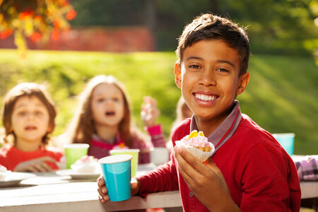 Close up view of Central Asian boy holding cupcakeの写真素材