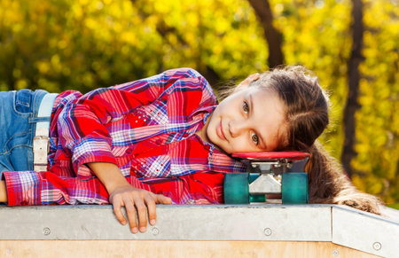 Beautiful girl laying with head on skateboardの写真素材