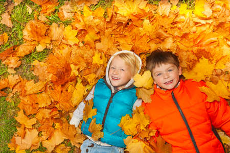 Two boys laying on the autumn leaves view from topの写真素材