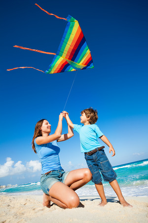 Beautiful woman and boy holding arms with kiteの写真素材