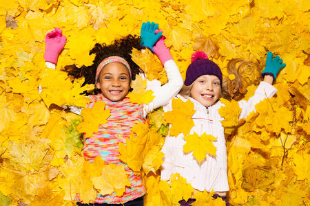 African and Caucasian girl covered in maple leaves