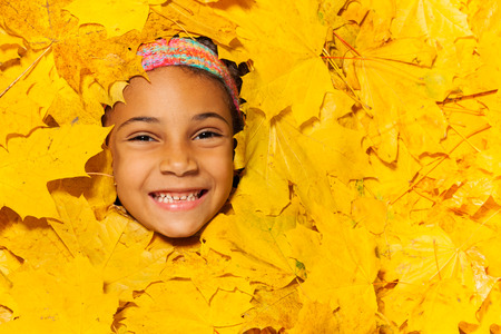 Face of a little African girl in autumn leaves