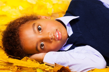 Little black boy lays on the autumn maple leavesの写真素材