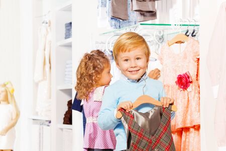 Boy with hanger and girl behind choosing clothesの写真素材