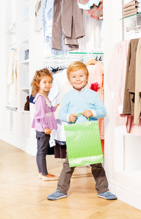Smiling boy with shopping bag and girl behindの写真素材