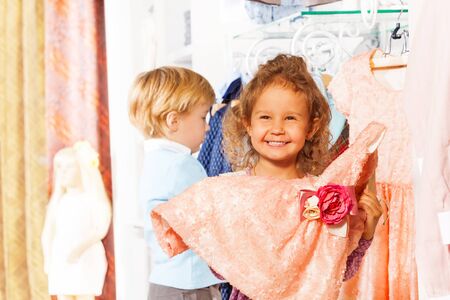 Laughing girl holds dress, boy behind her in shopの写真素材