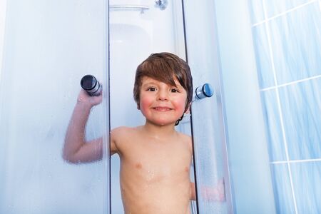 Portrait of little boy in shower cabin washingの写真素材