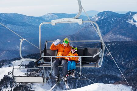 Man skier with child lift on ropeway chairの写真素材