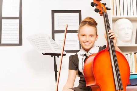 Smiling girl holds string to play violoncelloの写真素材