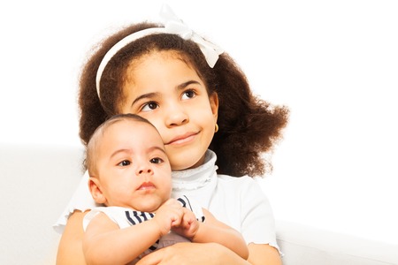 Beautiful African girl holds sister baby in armsの写真素材