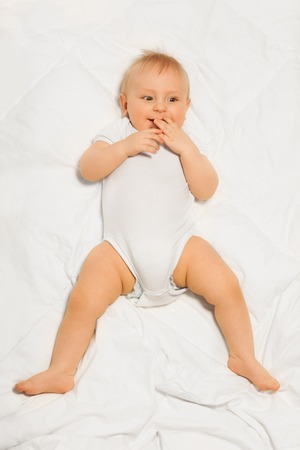 Chubby small baby with fingers near his mouthの写真素材