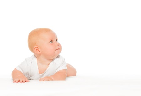 Chubby baby with turned head in white bodysuit on the white background crawling and laying on the...