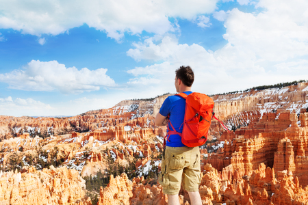 Man with orange rucksack standing with Bryce Canyon National Park view aloneの写真素材
