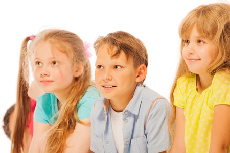 Group of happy boys and girls sit together in a line isolated on white smilingの写真素材