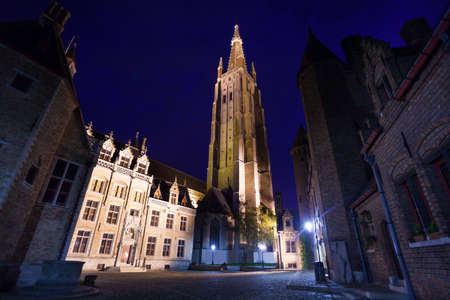 Church of Our Lady Bruges night view from cobblestone paved road in Brugesの写真素材