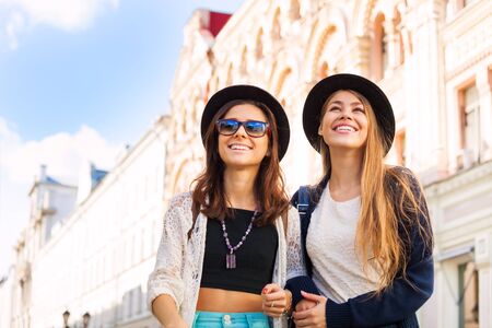 Young women walking together and admiring sightseeing attractions on the beautiful street during summer day timeの写真素材