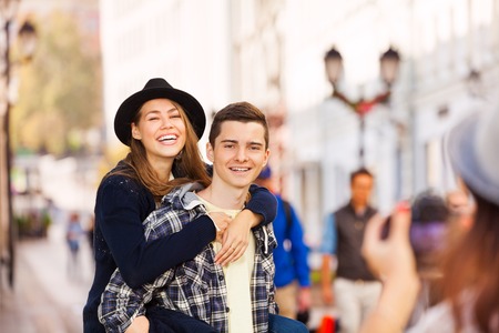 Boy holding laughing woman and girl shooting them with professional camera on the European street during summer day timeの写真素材