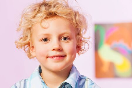 Handsome boy with curly blond hairs in the room