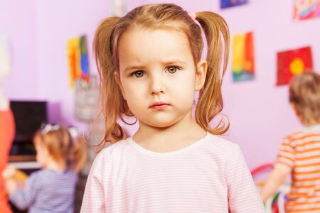 Portrait of calm little girl with kindergarten friends group on the back