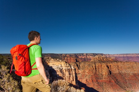 Close portrait from behind of young man standing on the edge of Grand canyonの写真素材