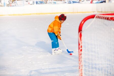 Little boy play hockey punching with stick puck to the gatesの写真素材