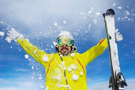 Man skier with beard throw snow up over blue sky wearing helmet and maskの写真素材