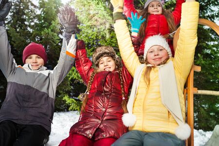 Close up picture of smiling friends, boy and girls, resting after winter games, raising their hands upの写真素材