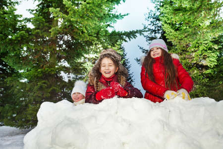 Tree Caucasian laughing girls playing snowballs at sunny winter dayの写真素材
